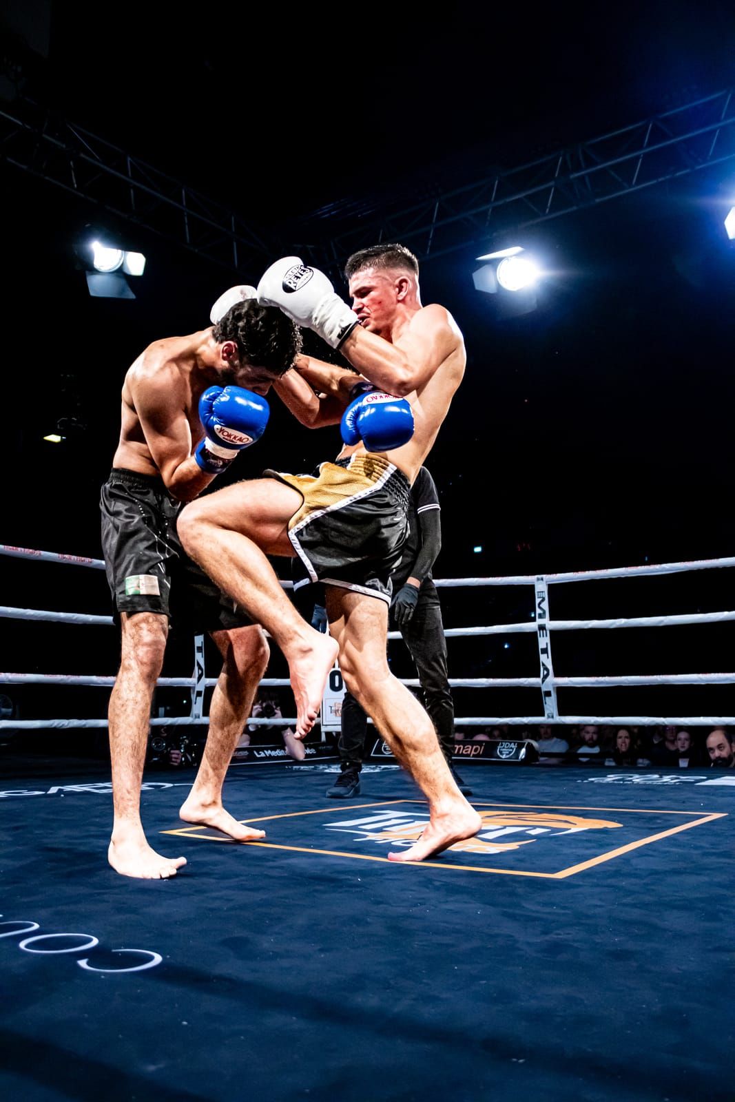 Corps à corps entre deux combattants sous les lumières du Palais des Sports